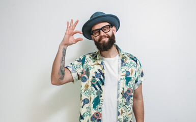 Some more, please. A cute hipster guy in a hat, with a beard gesticulates with his fingers, shows...