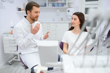 people, medicine, stomatology and health care concept - woman patient talking to male dentist and...