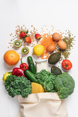 Cotton bag with vegetables and fruits on white background. Zero waste grocery shopping. Sustainable lifestyle concept. Plastic free items