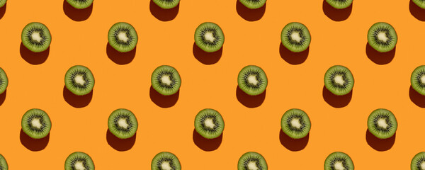 Pattern of green kiwi slices on bright orange background. Fruit abstract background. Summer bright concept