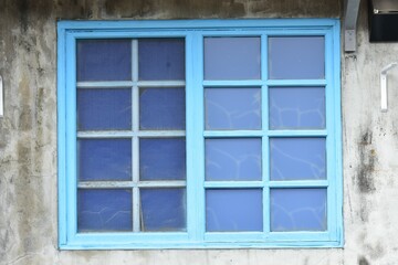 Fototapeta na wymiar old blue wooden window with shutters on the white mottled wall