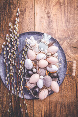 Easter eggs with pussy-willow branch on wooden kitchen table