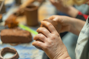 Close up of human hands making a clay mug. Pottery teaching class. Potter makes dishes from clay, ceramics.