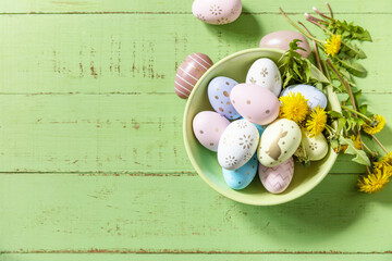 Happy Easter Holidays. Handmade Easter colorful eggs and spring flowers dandelions on a rustic wooden table. Easter composition. View from above. Copy space.