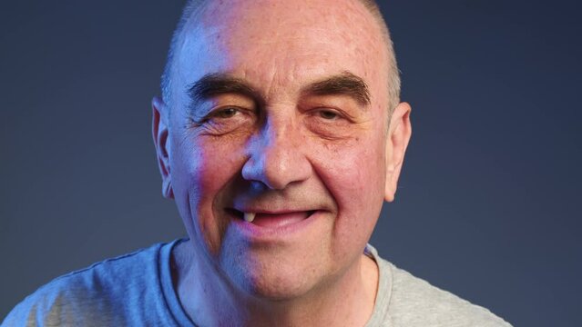 Elderly man puts false teeth into his mouth. Periodontal disease and missing teeth in an elderly man. Close up shot of a toothless male mouth