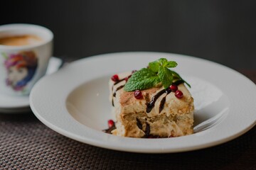 Closeup of Tiramisu on a white plate a cup of coffee blurred background