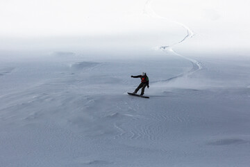 The backcountry snowboarder gracefully carves through the untouched powder snow, leaving behind a...