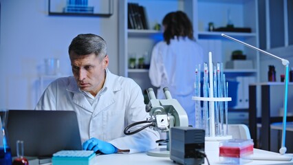 Male forensic laboratory worker checking criminal case details on computer