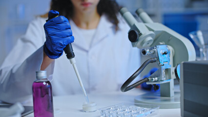 Laboratory scientist taking sample of liquid to examine it under microscope