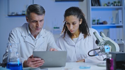 Focused scientists checking patient's test results on tablet, diagnostics