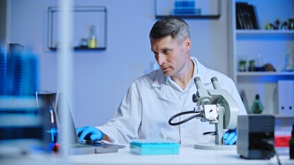 Laboratory scientist typing test results on laptop, checking with previous research