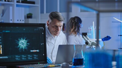 Biological laboratory scientist studying experiment results on laptop, research