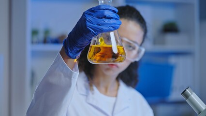 Woman laboratory scientist observing chemical reaction of liquid in flask, experiment 