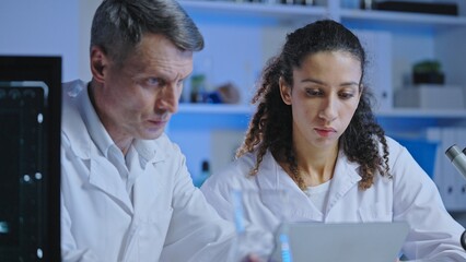 Two laboratory scientists examining results of experiment on computer, research