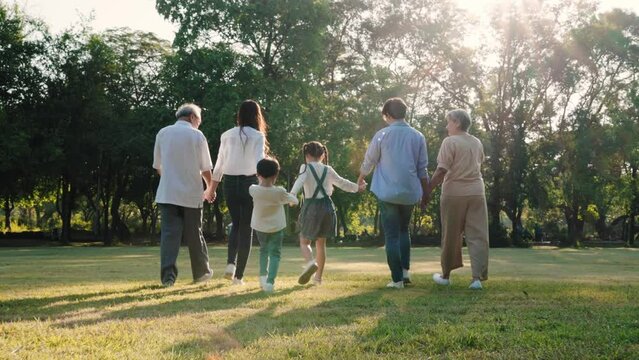 The back of Happy Asian family walking in the park together, Outdoor with big family and summer season concept