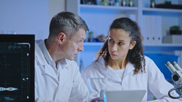 Laboratory scientists consulting with each other, working on medical research in laboratory