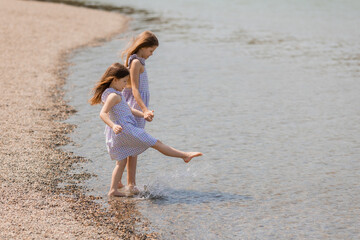 Naklejka premium two happy little girls are walking near the lake in summer. Earth Day. Children's Day.Space for text