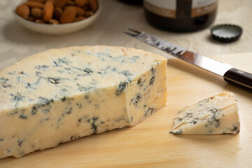 Piece of traditional English Stilton blue cheese close up on a cutting board