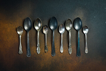 Set of vintage spoons. Old cutlery. Top view. On a dark stone background.