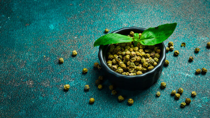 Fragrant green pepper peas in a bowl. Spices and condiments. Top view. On a green background.