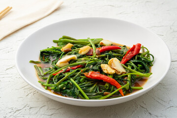 Thai stir-fried water morning glory with Oyster Sauce in white plate