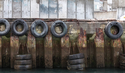 Grungy mooring wall with rubber bumpers made of old used car tyres © evannovostro