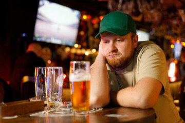 bearded redhead man with glasses of beer falls asleep in a bar