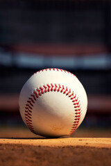 A white leather baseball lying on top of the pitcher's mound
