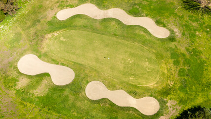 Aerial view of an empty golf course with green hills and sand bunkers. The sports club is empty and nobody is playing. Sports concept.