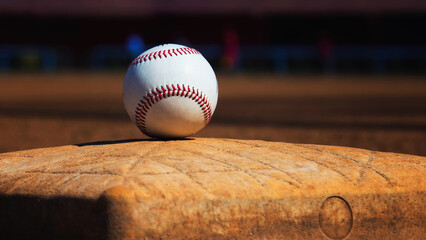 A white leather baseball lying on top of the pitcher's mound