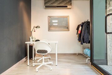 Plain white table of a beauty salon dedicated to the treatment of nails next to a donkey full of jackets and raincoats