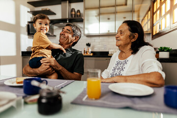 Happy grandparents having breakfast with their grandson - obrazy, fototapety, plakaty