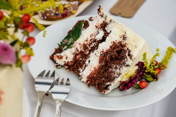 Stück einer Hochzeitstorte auf Teller mit zwei Kuchengabeln