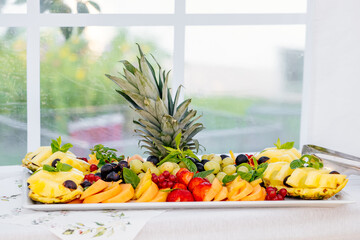 Obstplatte mit Ananas, Weintrauben, Honigmelone, Erdbeeren, Johannisbeeren, Minze als gesunder Snack und Erfrischung bei Sommerfest