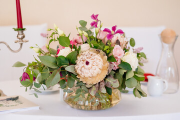 Protea oder auch Zuckerbüsche genannt in wilder Blumendeko mit Pfingstrosen und grünen Blätter...