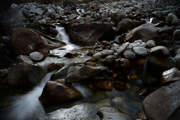 A long exposure shot of a small water stream with stones