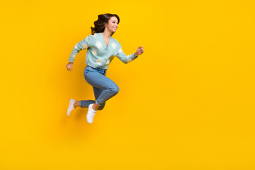 Fototapeta na wymiar Full length photo of excited pretty lady dressed teal cardigan jumping high running fast emtpy space isolated yellow color background