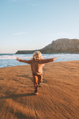 Happy child girl running on beach emotional kid 4 years old kid raised hands family travel...