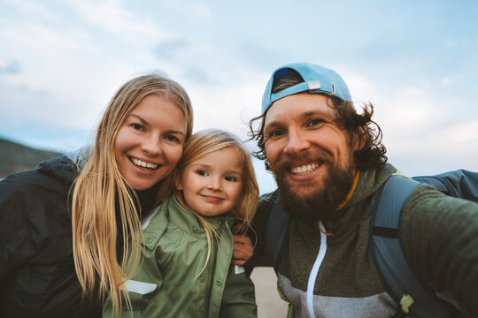 Family selfie man and woman with child outdoor mother and father with kid daughter happy smiling faces travel lifestyle together