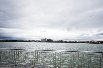 Lake promenade with glass building multistorey residental house on background.