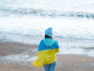 Fototapeta na wymiar brunnete woman wearing in blue hoodie and blue hat with national flag of Ukraine