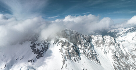 Alpine landscape with peaks covered by snow and clouds. Magical clouds covering peaks of the mountains at the famous St. Anton am Arlberg ski resort.