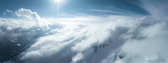 Obraz premium Alpine landscape with peaks covered by snow and clouds. Magical clouds covering peaks of the mountains at the famous St. Anton am Arlberg ski resort.