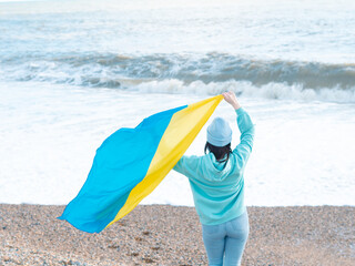 brunnete woman wearing in blue hoodie and blue hat with national flag of Ukraine