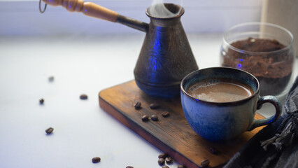 a cup of fragrant Turkish coffee on a white table, ground coffee, cezve and steam from a hot drink