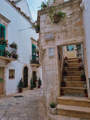 Fototapeta na wymiar Charming tiny Italian alley street with decorated balconies at the coastal town of Polignano a Mare, PugliaItaly, Italia