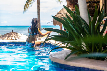 Beautiful woman relaxing out of a pool with the Caribbean Sea in the background, this is a tropical place and ideal for tourism and summer vacations.