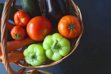 Two wicker baskets with healthy seasonal fruit and vegetable. Dark background, top view.