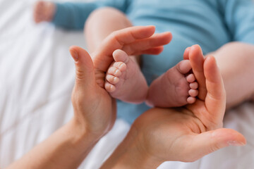 mom holds baby's small feet close-up