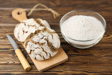 Fresh sourdough bread on a wooden background. Freshly baked homemade rye bread, with rye flour in a glass plate. Selective focus
